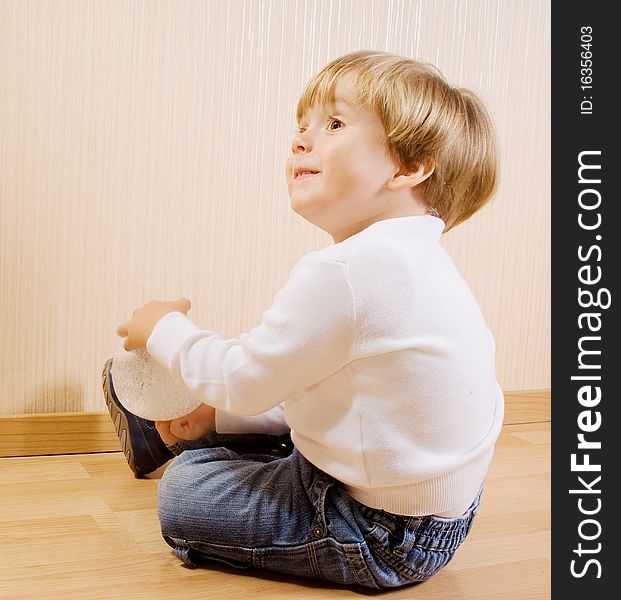 The child playing on the wood floor with white ball. The child playing on the wood floor with white ball