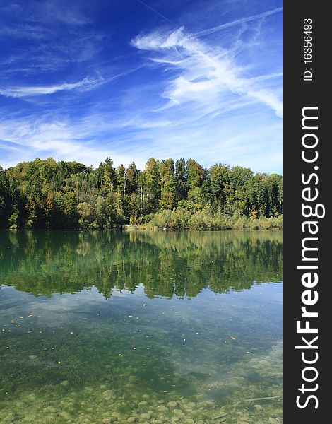Green lake with colorful wood and blue sky in autumn. Green lake with colorful wood and blue sky in autumn