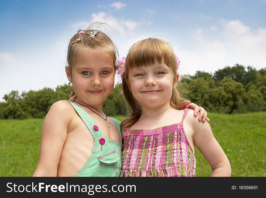 Two little girls in the summer park (one with closed eyes from bright light). Two little girls in the summer park (one with closed eyes from bright light)