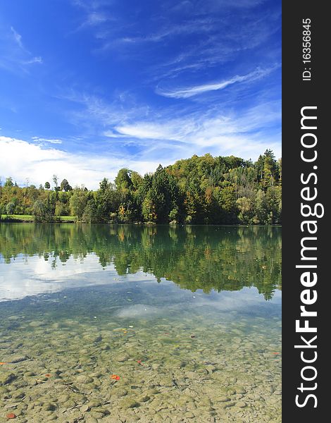 Green lake with colorful wood and blue sky in autumn. Green lake with colorful wood and blue sky in autumn