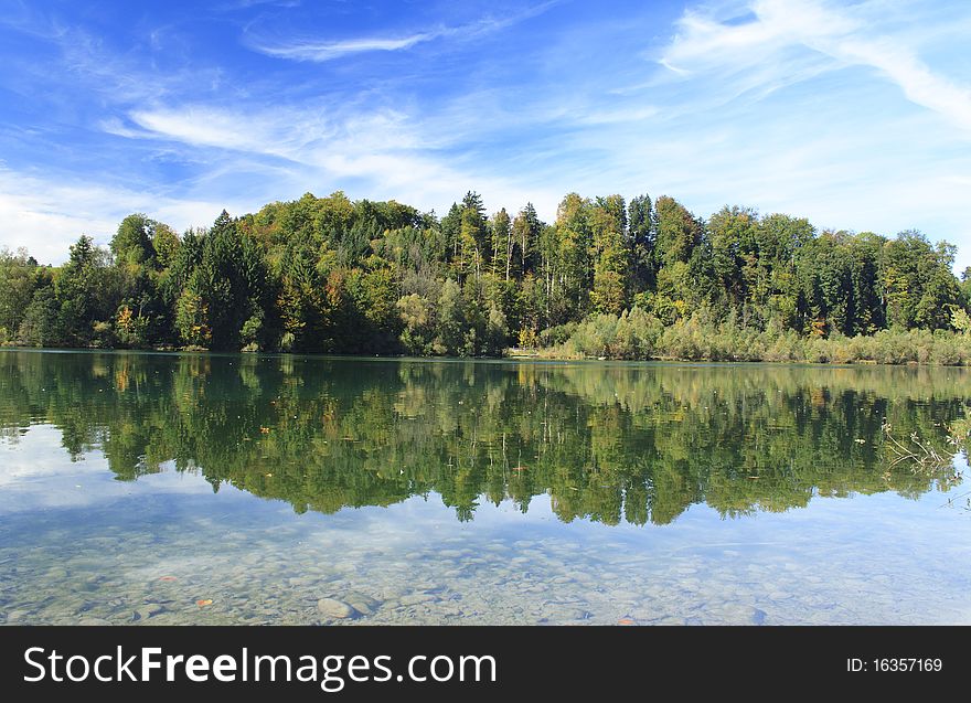 Green lake with colorful wood and blue sky in autumn. Green lake with colorful wood and blue sky in autumn