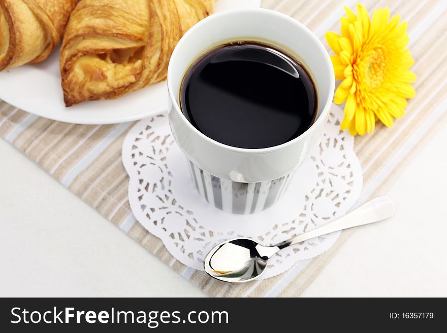 A cup of black coffee, croissants and yellow flower. A cup of black coffee, croissants and yellow flower