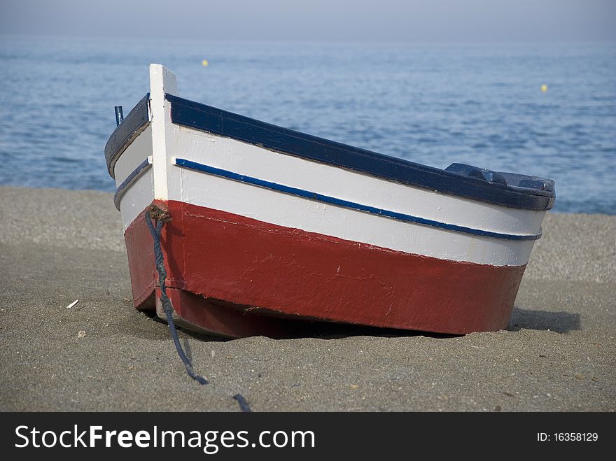 Red white and blue fishing boat stranded on a beach