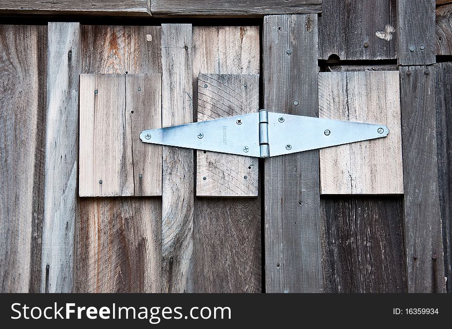 A new door hinge repairing an old barn door with natural, rough-hewn lumber. A new door hinge repairing an old barn door with natural, rough-hewn lumber