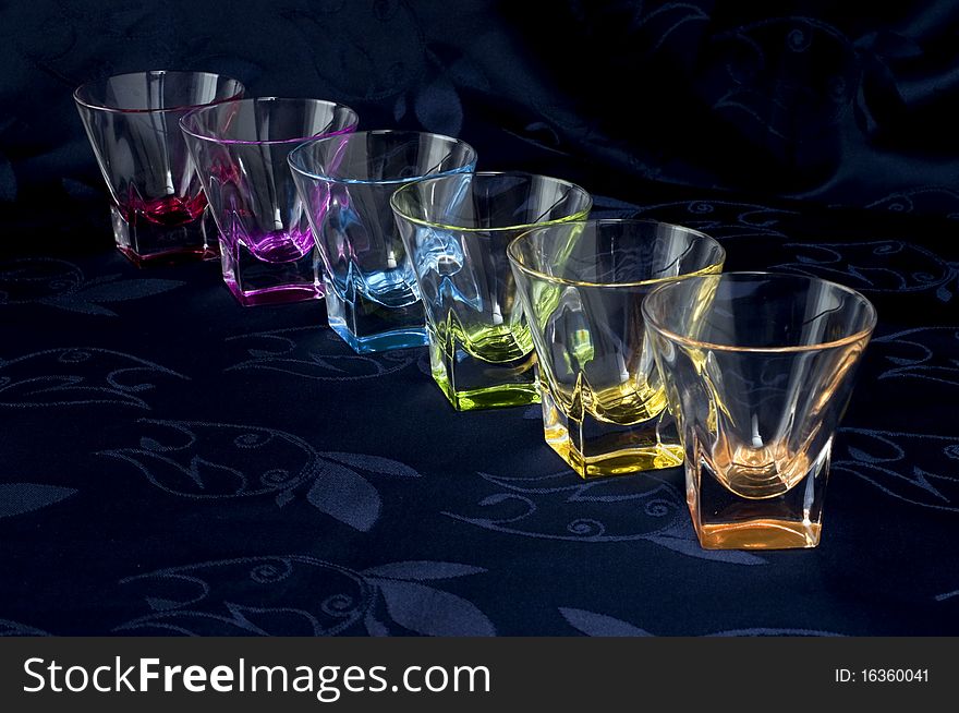 Colored glass jug and glasses on a dark background. Colored glass jug and glasses on a dark background