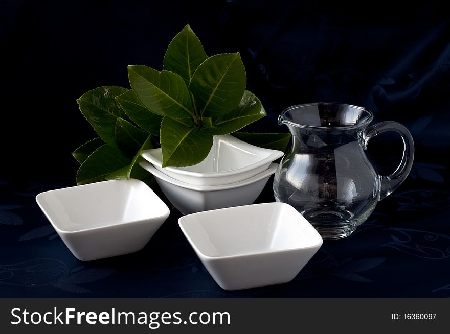 Containers in white ceramic pitcher and glass on a dark background. Containers in white ceramic pitcher and glass on a dark background