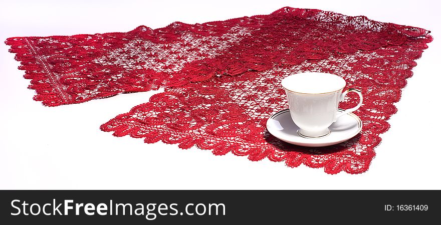 White cup on red doily with lace