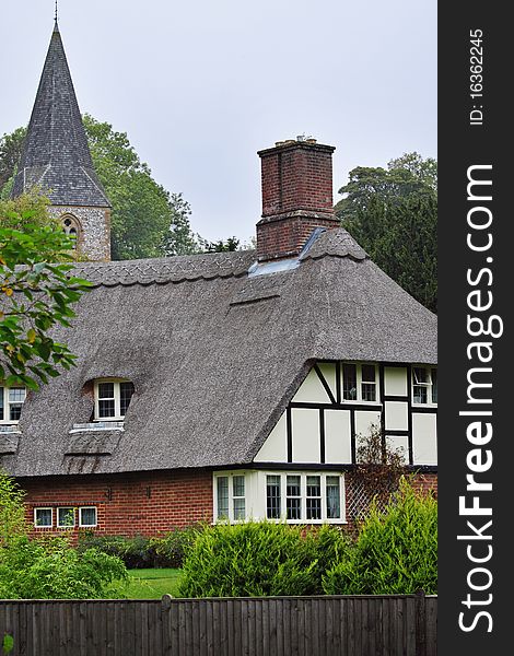 Traditional Thatched English Village Cottage with Church Steeple behind