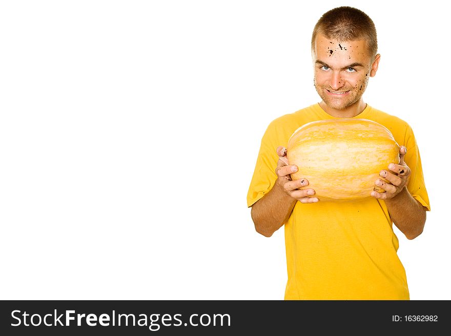 Handsome young man holding a big yellow pumpkins in their hands. An evil smile. Lots of copyspace and room for text on this isolate. Handsome young man holding a big yellow pumpkins in their hands. An evil smile. Lots of copyspace and room for text on this isolate