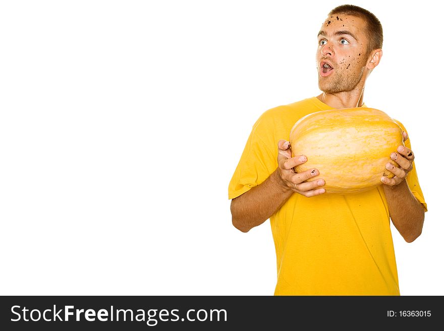 Handsome young man holding a big yellow pumpkins in their hands. Face expressed surprise, looks away. Lots of copyspace and room for text on this isolate. Handsome young man holding a big yellow pumpkins in their hands. Face expressed surprise, looks away. Lots of copyspace and room for text on this isolate