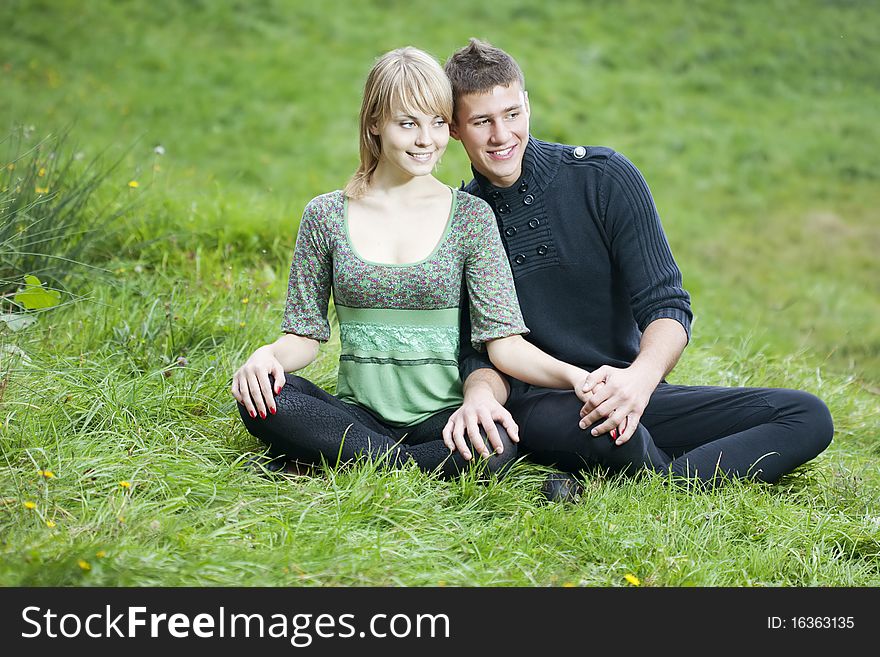 Young couple embraces in a green meadow. Young couple embraces in a green meadow
