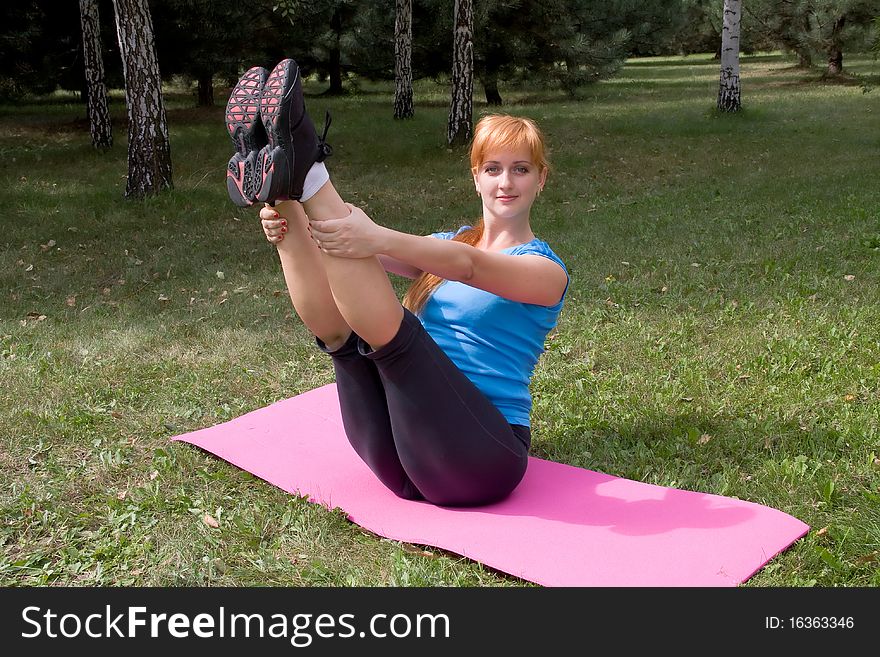 Woman engages in yoga, sits on buttocks in splits. Woman engages in yoga, sits on buttocks in splits