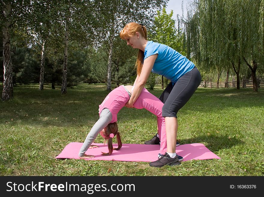 A mother and daughter engage in fitness on nature