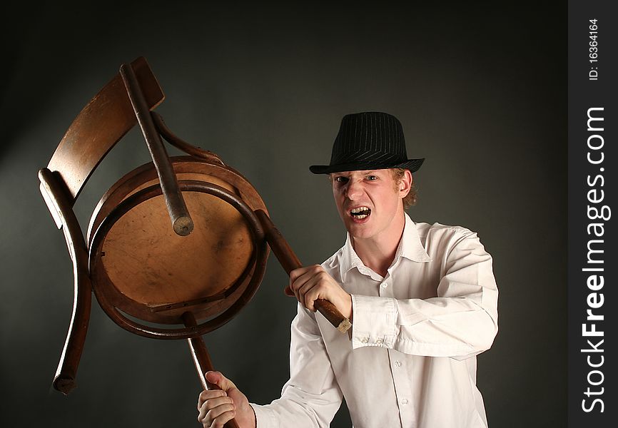 Aggressive guy with chair on dark background. Aggressive guy with chair on dark background