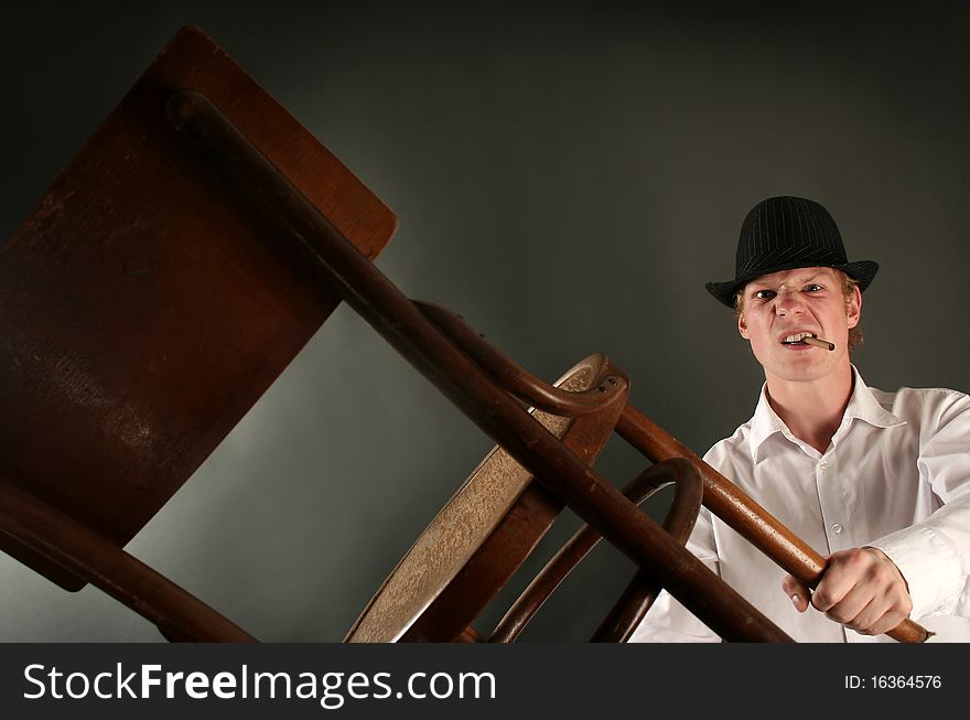 Aggressive guy with chair on dark background