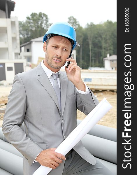 Businessman with helmet checking site under construction. Businessman with helmet checking site under construction