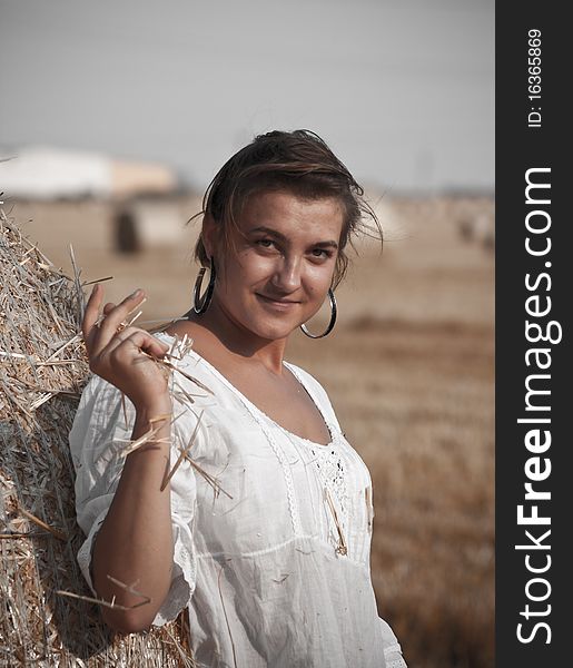 Woman in the white tunic leaning against the beam of straw. Woman in the white tunic leaning against the beam of straw