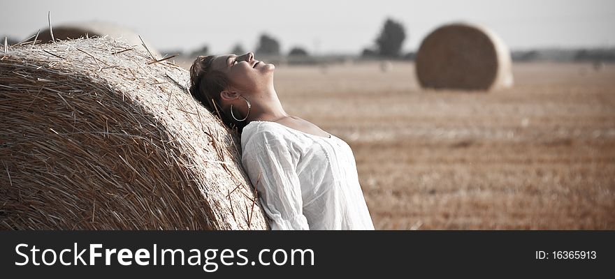 Woman in the white tunic leaning against the beam of straw. Woman in the white tunic leaning against the beam of straw