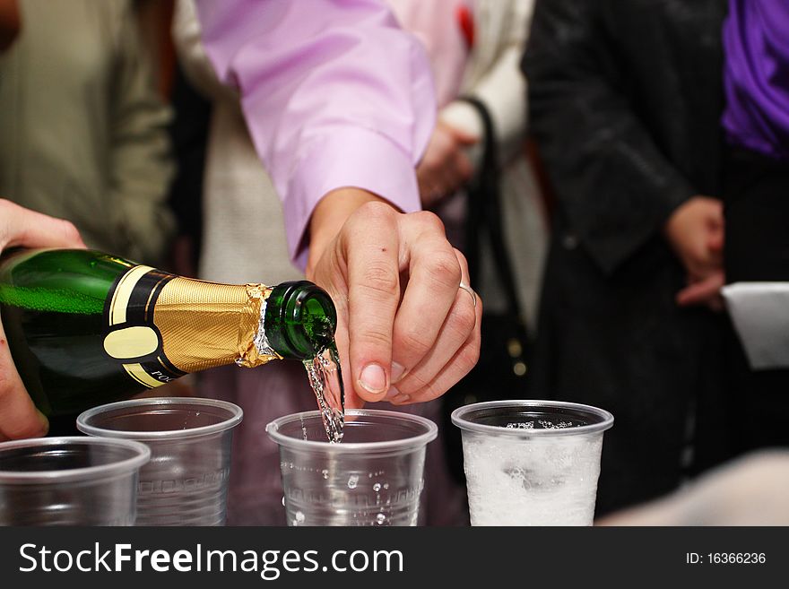 Champagne poured from the boatle to plastic pour. Focus is under the bottle neck