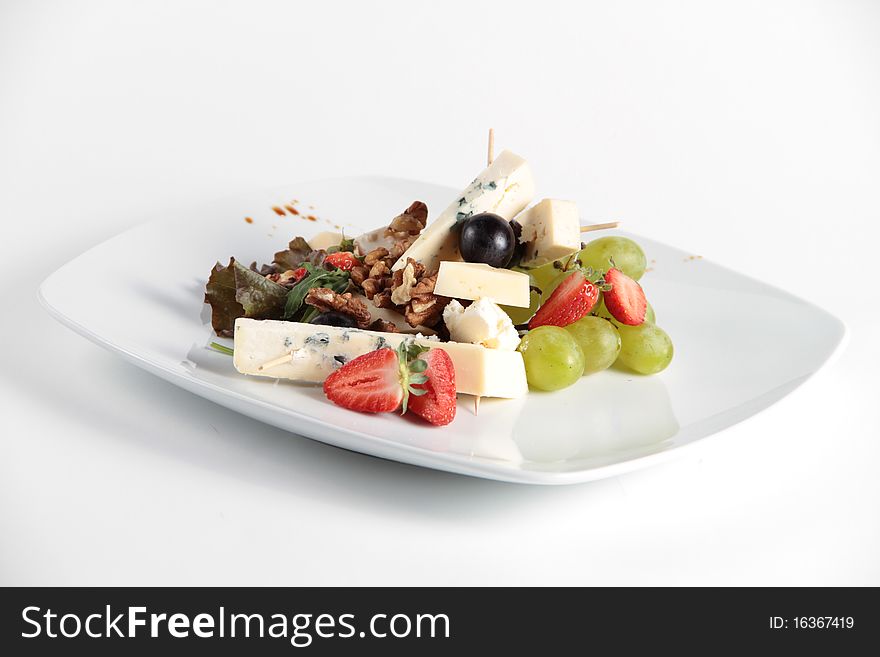 Beautifully decorated cheese and fruit salad served on a white plate. Beautifully decorated cheese and fruit salad served on a white plate