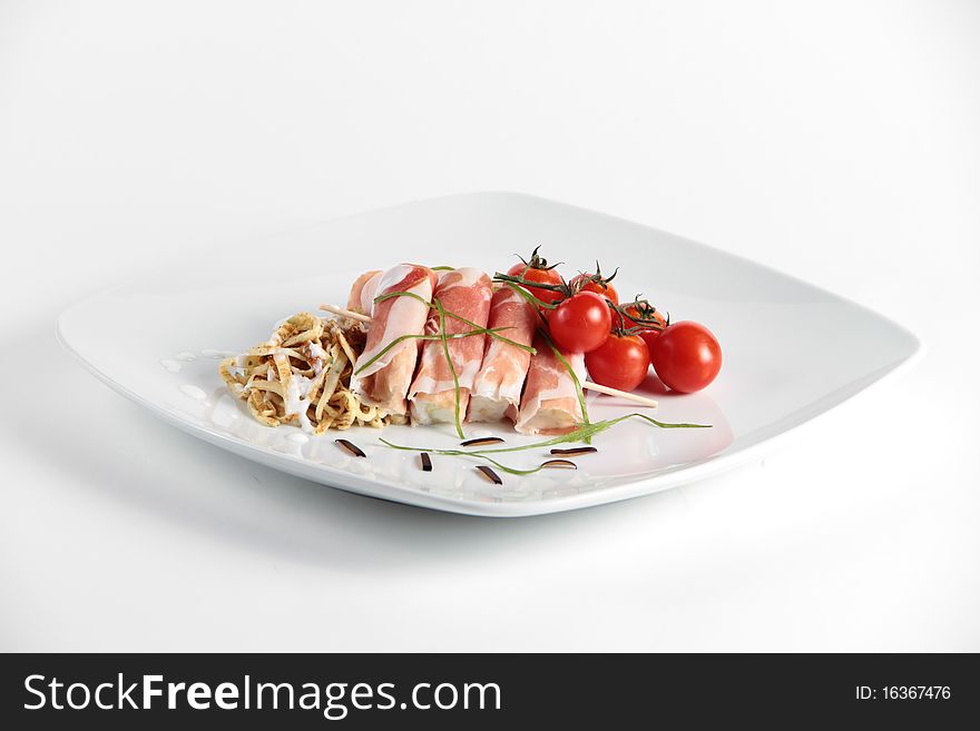 Smoked ham rolls with cherry tomatoes on a white plate. Smoked ham rolls with cherry tomatoes on a white plate