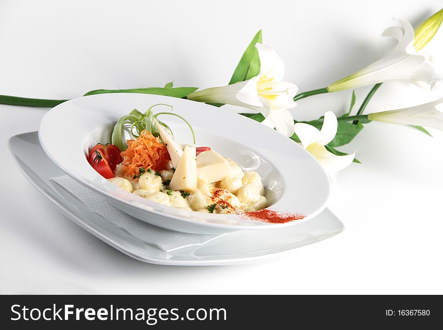 Italian pasta with cheese and flowers in the backg