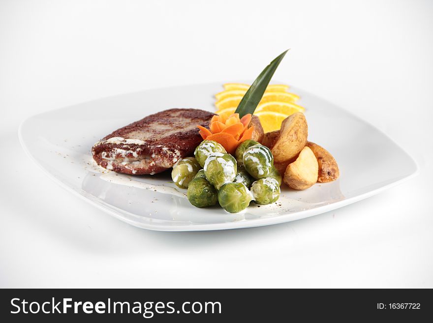Beaf stake served and decorated with vegetables on a white plate. Beaf stake served and decorated with vegetables on a white plate