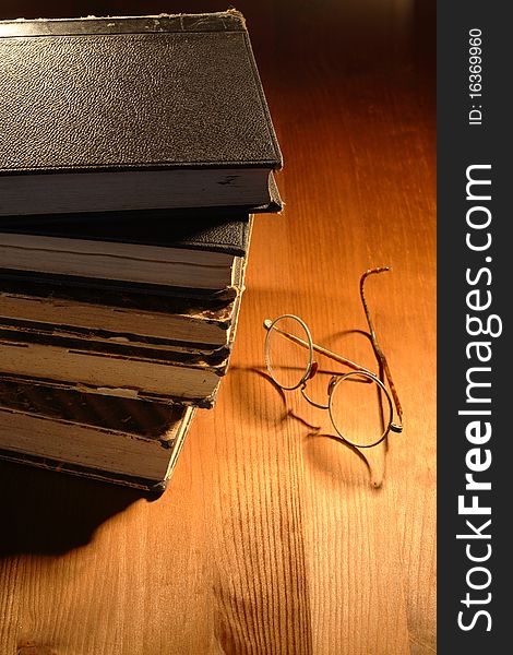 Very old eyeglasses near books lying on nice wooden background. Very old eyeglasses near books lying on nice wooden background