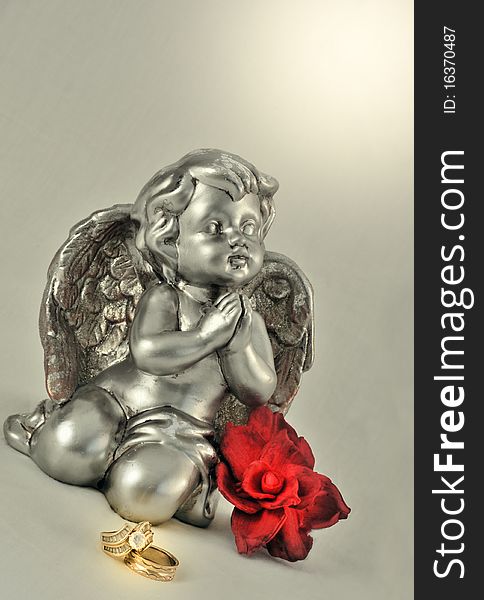 Praying angle with gold rings and red flower. Praying angle with gold rings and red flower