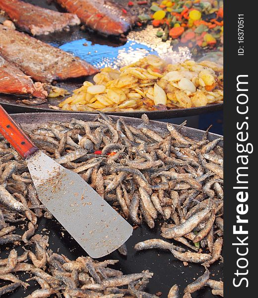 Frying whitefish and salmon in huge iron pans. Frying whitefish and salmon in huge iron pans