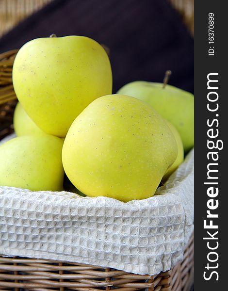 yellow apples in a wicker basket on the table. yellow apples in a wicker basket on the table