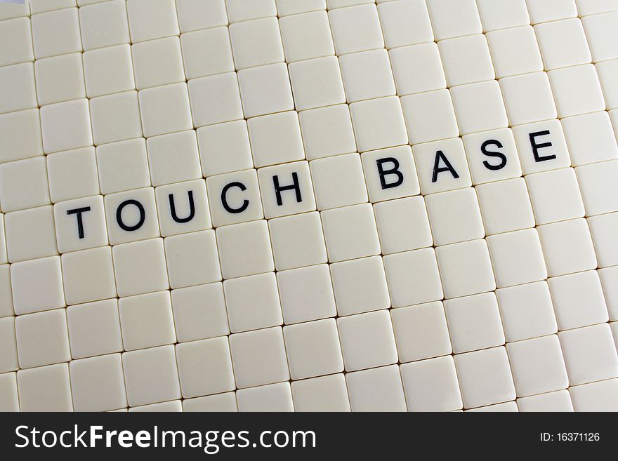 The words 'touch base' spelled out in tiles with blank tiles around them.