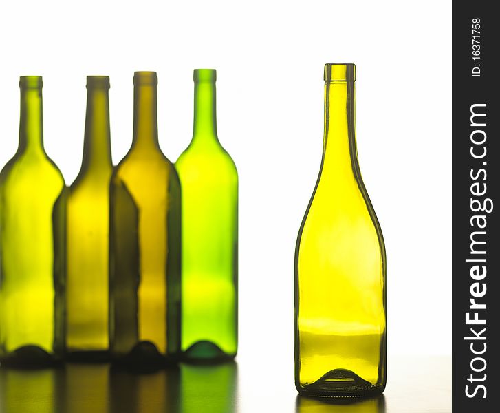 one green wine bottle next to four in the background. one green wine bottle next to four in the background