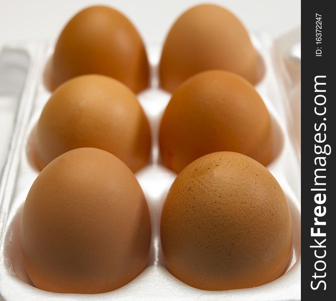 Six brown eggs in white egg box