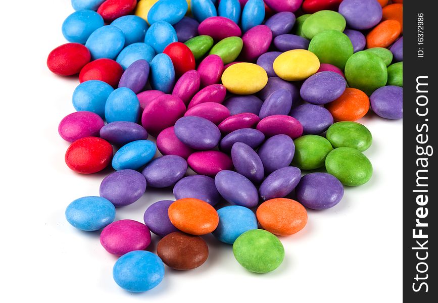Bright multi colored sweets spilling over a white background. Bright multi colored sweets spilling over a white background