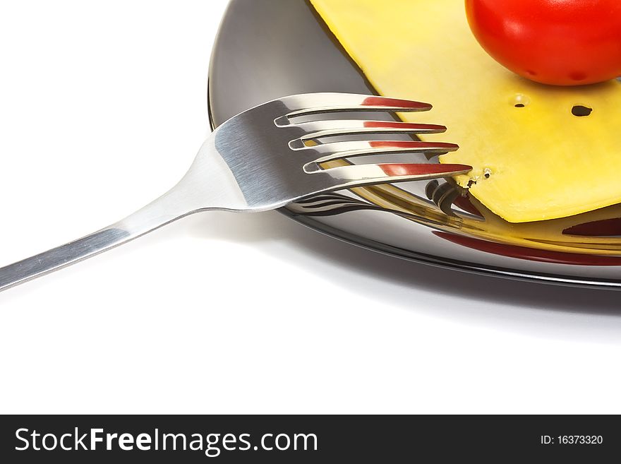 Red tomato and cheese on a black high-gloss plate with stainless fork. Red tomato and cheese on a black high-gloss plate with stainless fork