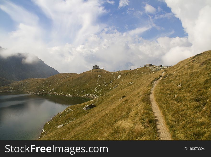 Lake Zancone pastures with mountains and clouds. Lake Zancone pastures with mountains and clouds