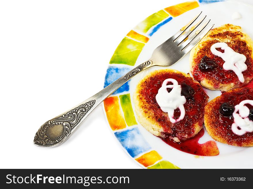 Cottage cheese pancakes with sour cream and blackcurrant jam on a colorful plate with fork. Cottage cheese pancakes with sour cream and blackcurrant jam on a colorful plate with fork