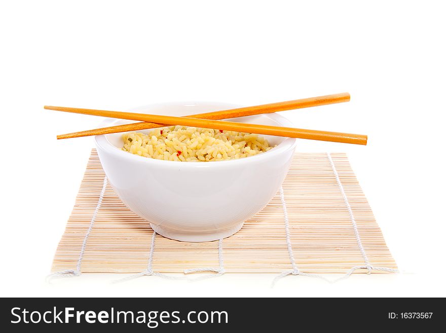 Chopsticks on top of a bowl yellow rice on bamboo mate isolated on white background. Chopsticks on top of a bowl yellow rice on bamboo mate isolated on white background