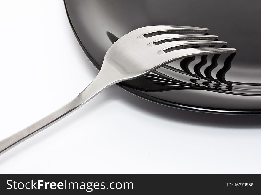 Black high-gloss plate with stainless fork. Black high-gloss plate with stainless fork