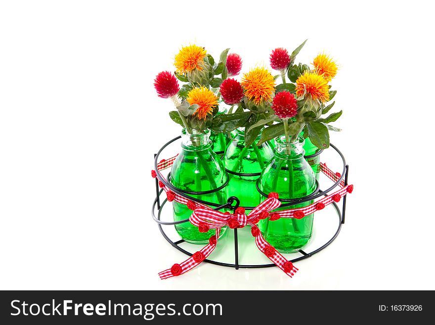 Orange and red flowers in five glass vases in green liquid water