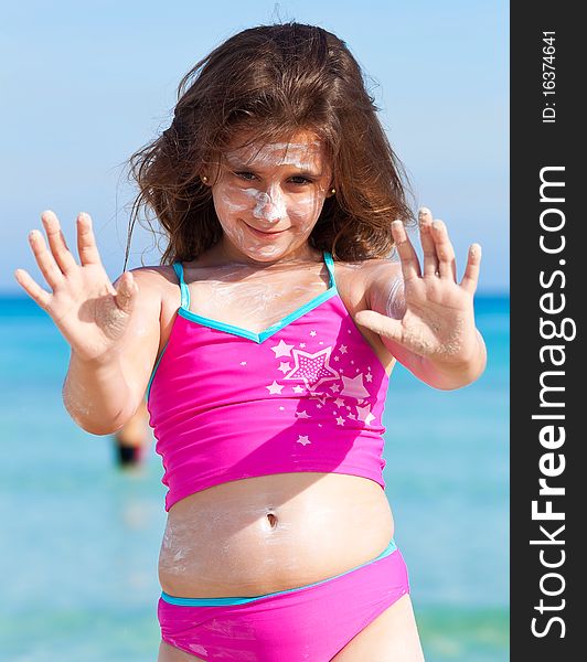 Beautiful girl on a tropical beach with sun cream on her face
