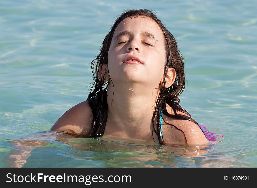 Beautiful girl on a swimming suit sitting in the water on a tropical beach. Beautiful girl on a swimming suit sitting in the water on a tropical beach
