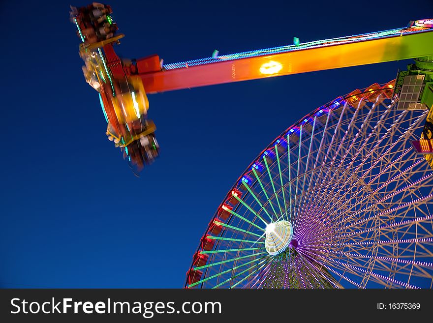 Ferris wheel and carnival ride at night. Motion blur