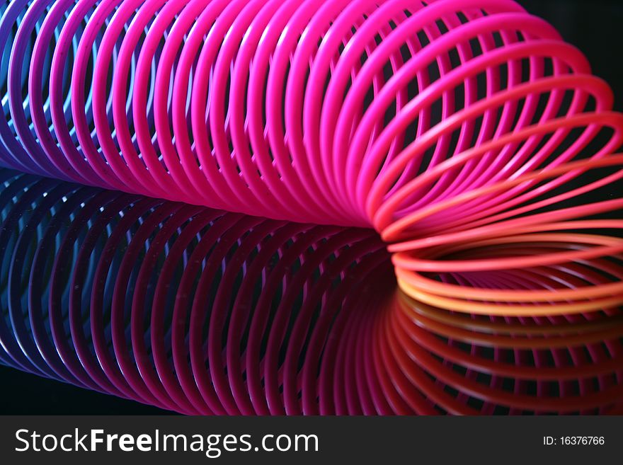 Colored spiral made of plastic over black background. Colored spiral made of plastic over black background
