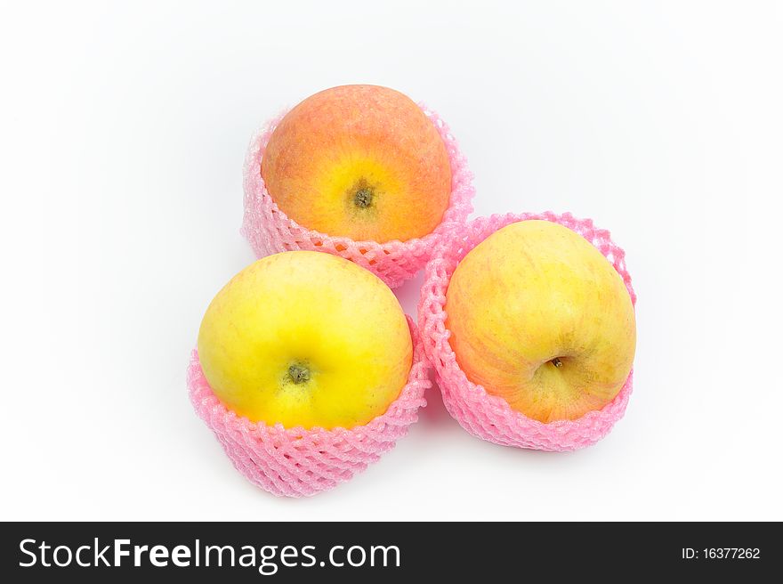 Close up of three apple shipping net on a white surface.