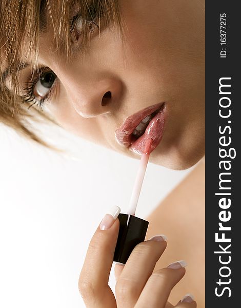 Pretty young woman applying liquid glossy lipstick
