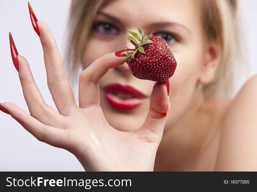 women with long red nails holding single strawberry. women with long red nails holding single strawberry