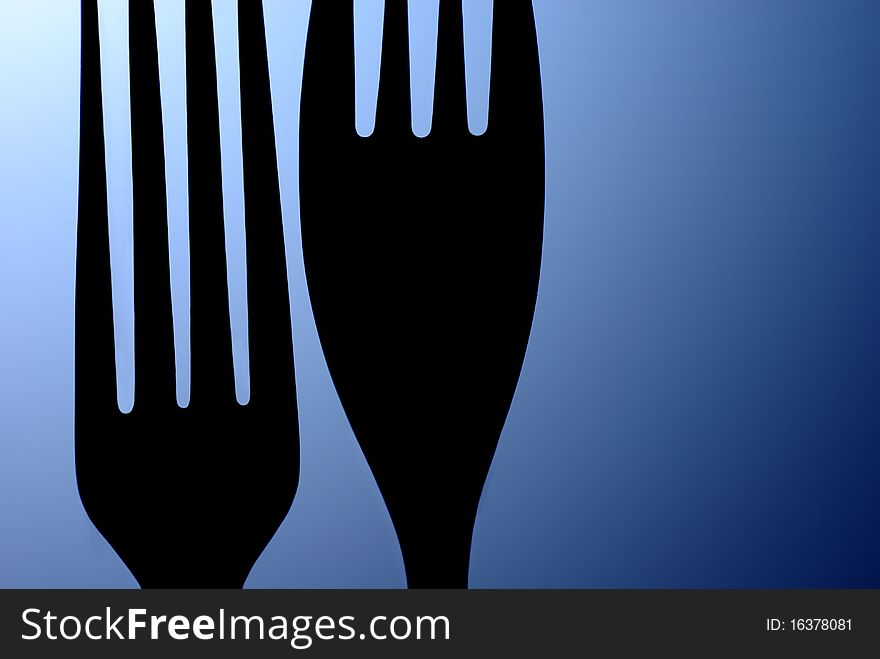 Black silhouette of the two table forks on a blue background