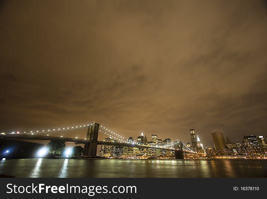 The iconic Brooklyn Bridge stretches across the East River on a cloudy evening. The iconic Brooklyn Bridge stretches across the East River on a cloudy evening